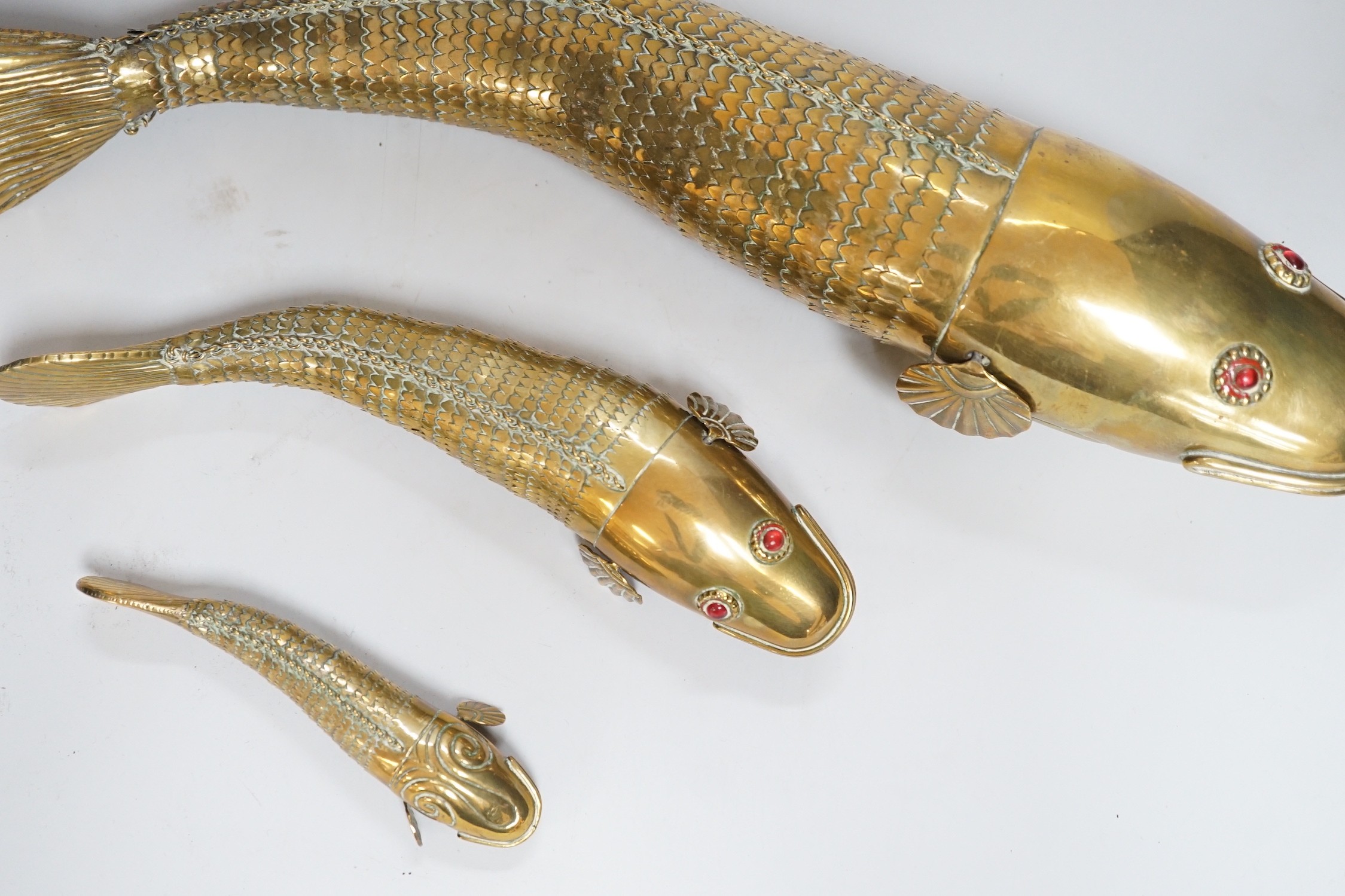 A set of three graduated brass articulated fish, largest 43.3cms long